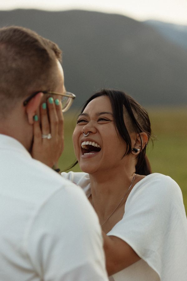 A joyful woman laughing with a man outdoors.