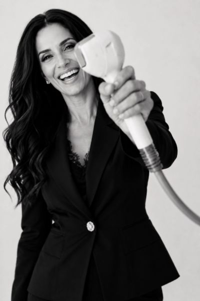 Smiling woman in black suit holding a device towards the camera.