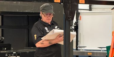 Person in work attire reading papers in a workshop setting.