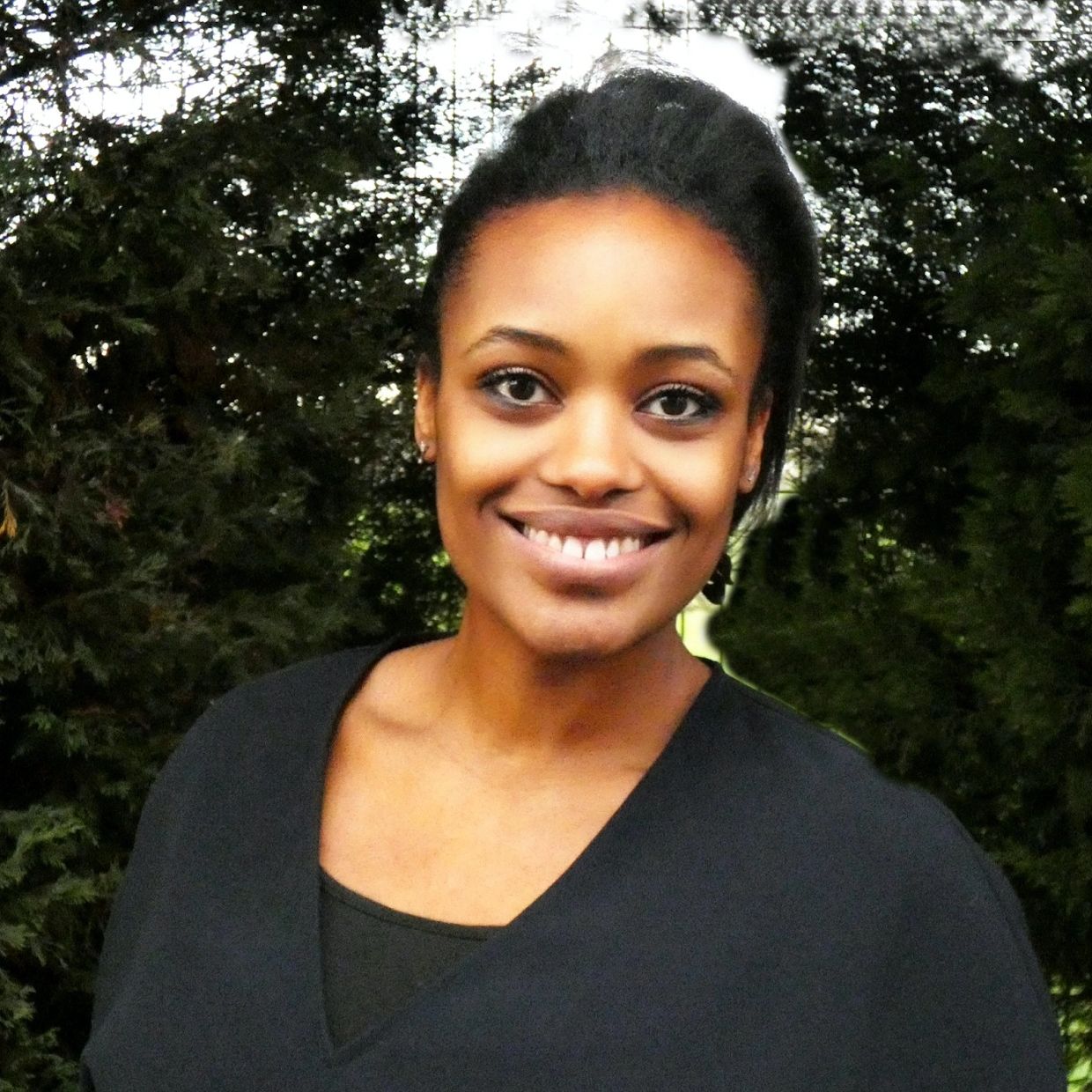 Smiling woman outdoors with trees in the background.