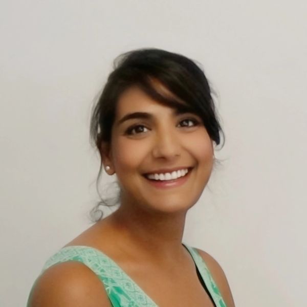 Smiling woman with dark hair in a green top against a plain background.