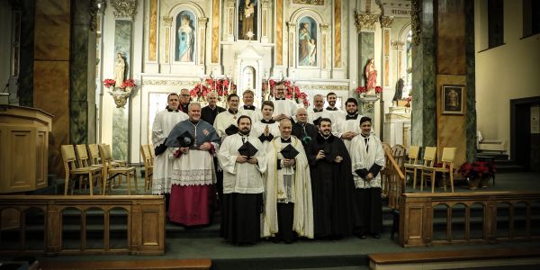 Group of priests posing inside a decorated church altar area.