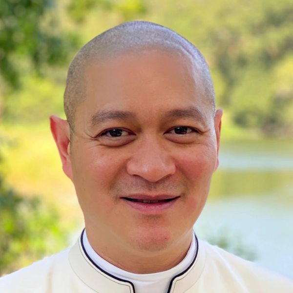 Smiling man in white shirt with nature background.