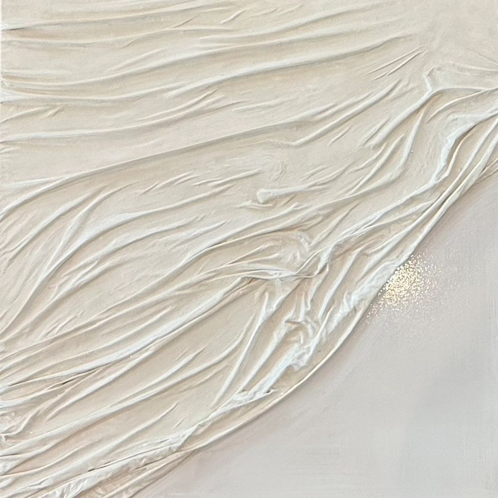 Close-up of textured, cream-colored fabric with intricate folds and light reflections.