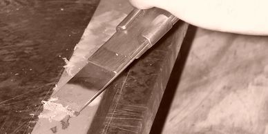 Using a utility knife to scrape a surface.