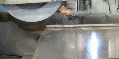 Grinding machine smoothing a metal surface.