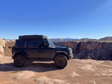 Off-road vehicle parked on rocky terrain with cliffs.