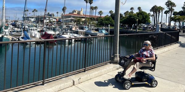 Senior citizen riding mobility scooter enjoys view at Santa Barbara Harbor 