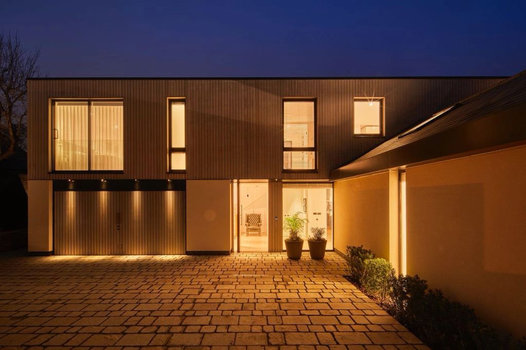 Modern house exterior illuminated at night with warm lighting.