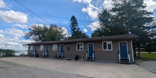 A long building with several blue doors under a partly cloudy sky.