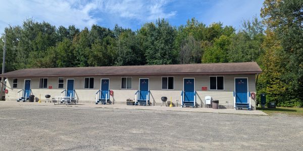 Single-story motel with blue doors and picnic tables outside.