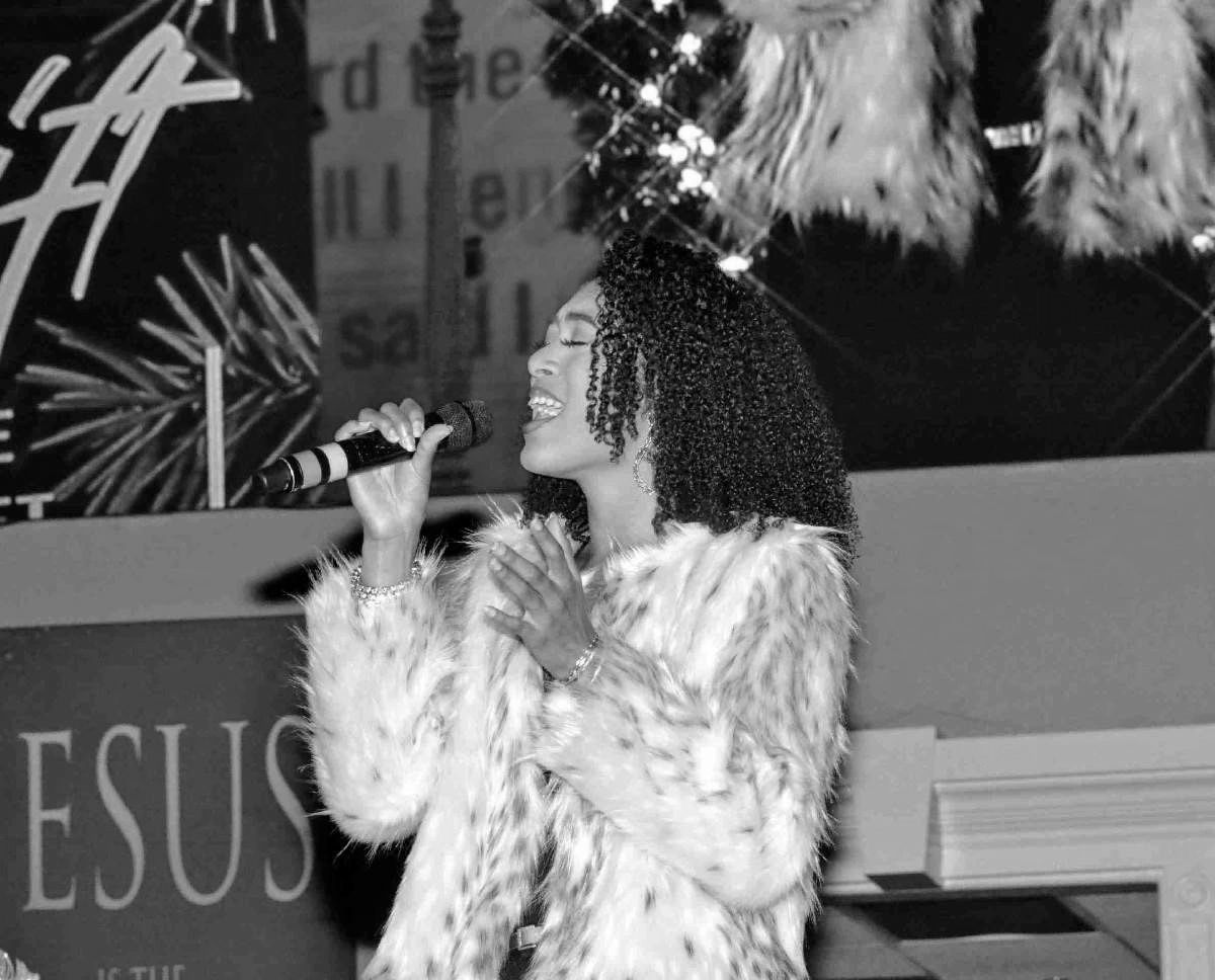 Woman singing passionately with a microphone in hand.