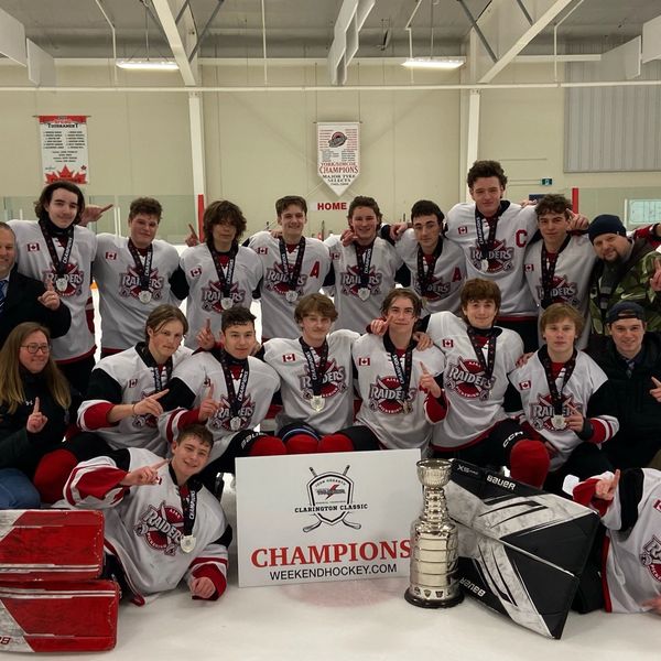 Youth hockey team celebrates winning the Clarington Classic championship with trophy on ice rink.