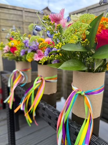 Colorful wildflower bouquets in rustic holders with rainbow ribbons.