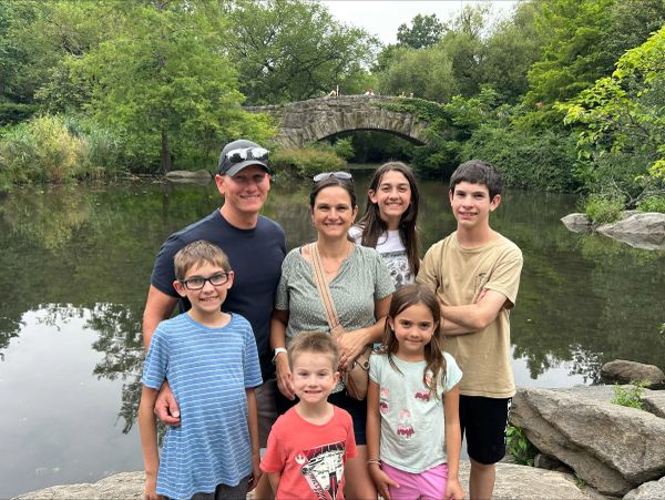 Family posing by a stone bridge and pond.
