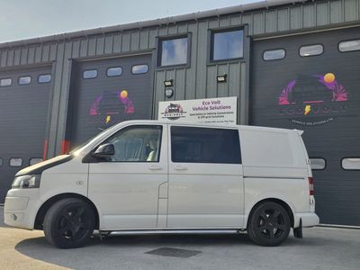 White van parked outside a garage with custom black rims and tinted windows.