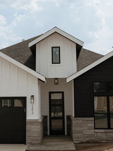 Modern house exterior with contrasting black and white siding and stone accents.