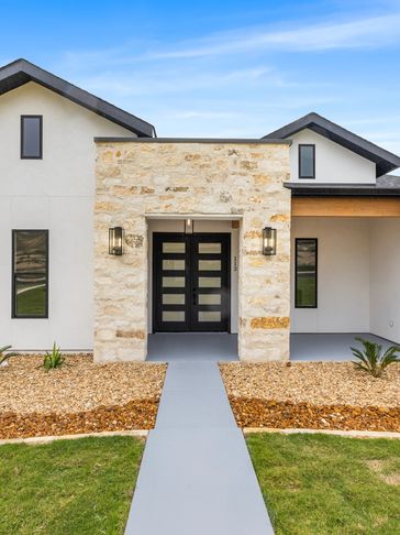 Modern house entrance with stone facade and black double doors.