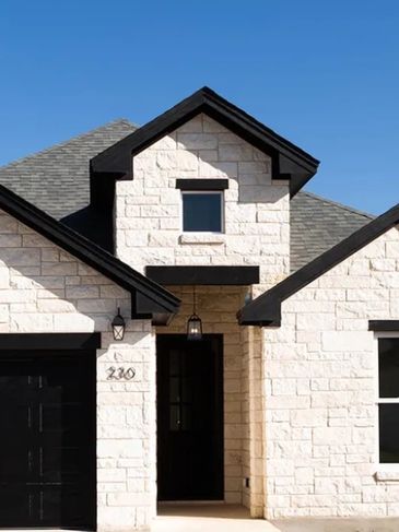 Modern house entrance with white stone walls and black trim.