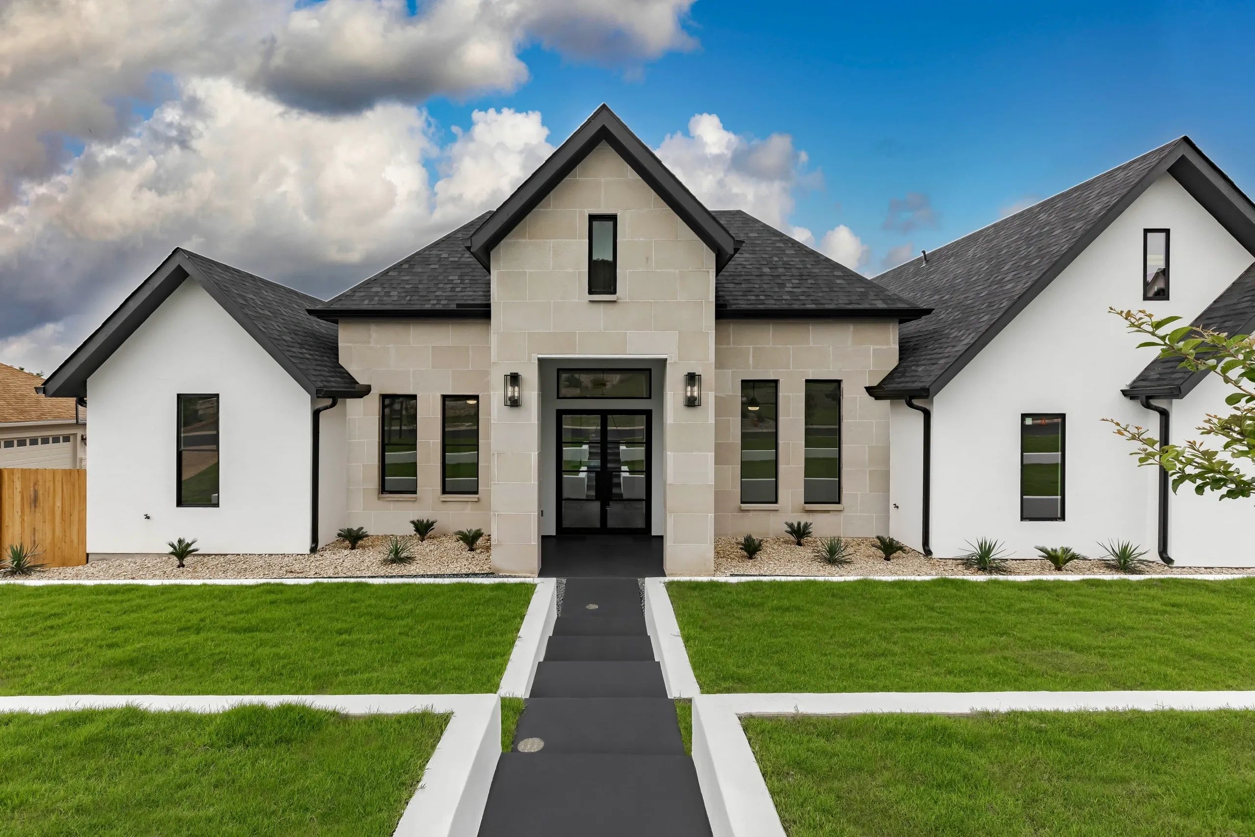 Modern house with a sharp roof and neatly landscaped front yard.