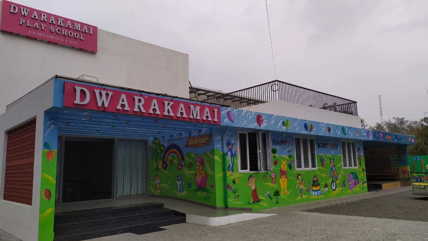 Colorful exterior of Dwarakamai Play School with cartoon murals and balloons.