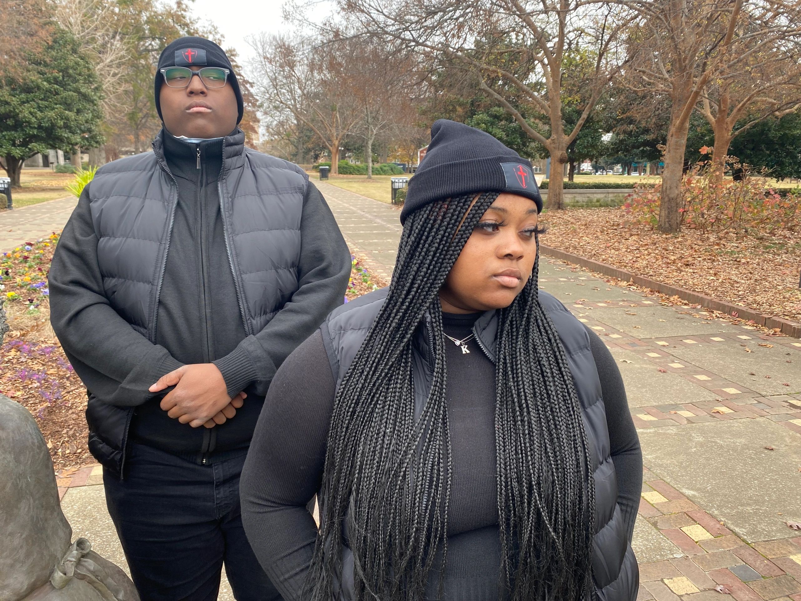 Two people in black winter clothing looking away in a park.