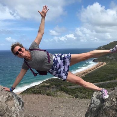 Woman balancing horizontally between two rocks by the sea.