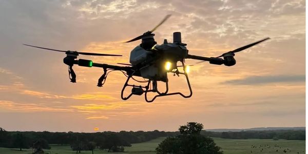 Drone flying at sunset with lights on.