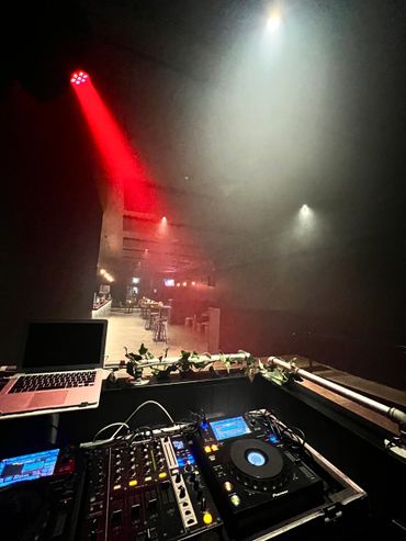 DJ booth setup with lighting effects in a dimly lit club.