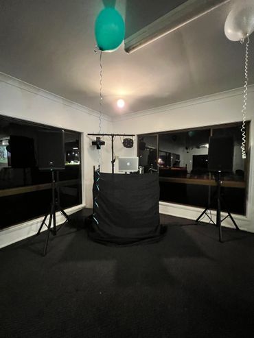 DJ setup with speakers and balloons in a dim room.