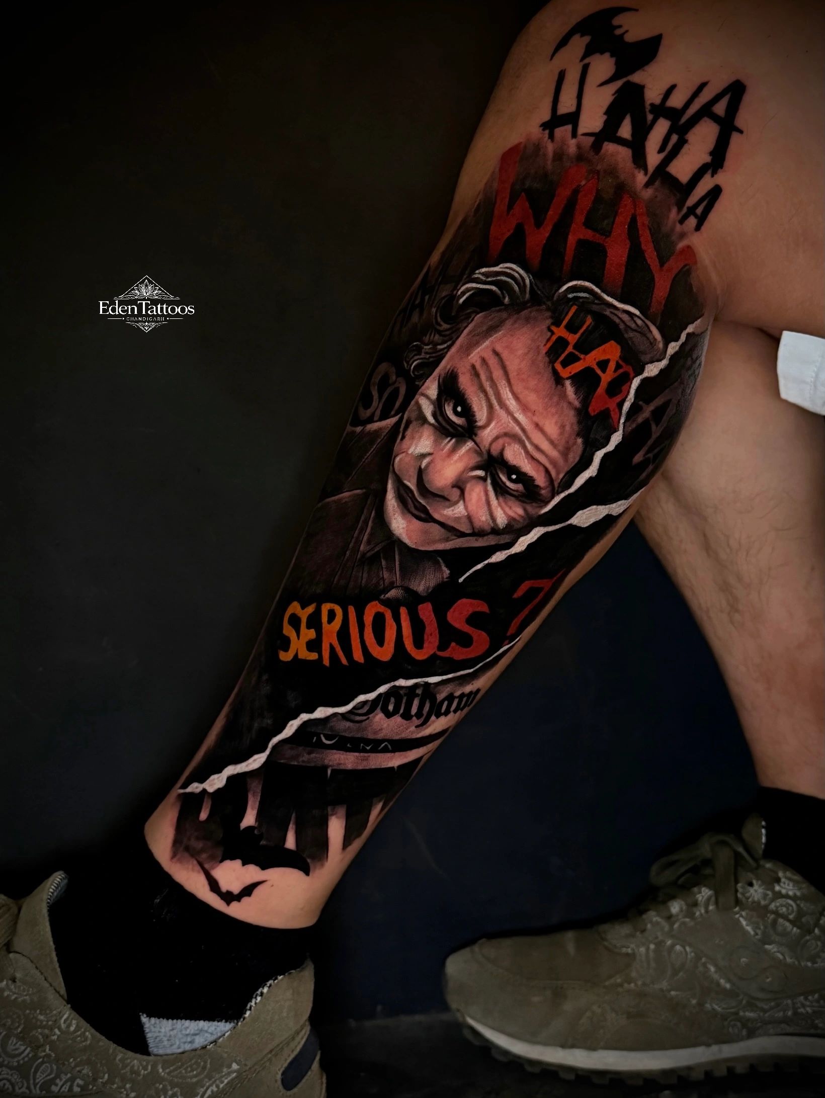 Realistic Joker tattoo;Why so serious?" text and Gotham theme on leg.