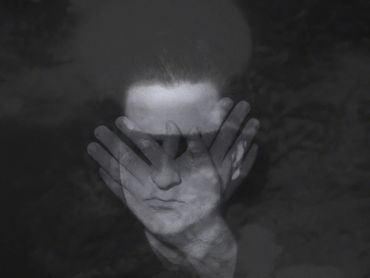 a transparent dream ghoul with closed eyes and crossed hands partially obscuring its face.