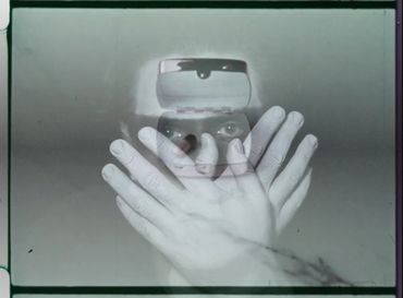a dream ghoul peers through the fingers of hands obscuring its face. it mocks the watcher.