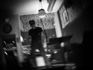 Blurry black and white image of a person standing indoors.