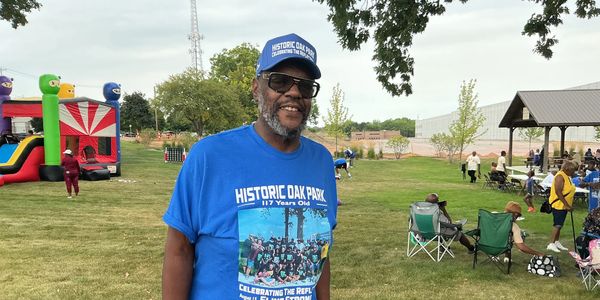 Man wearing a Historic Oak Park t-shirt and cap at an outdoor event.