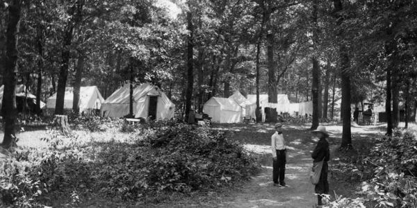 Black and white image of a campsite in a forest.