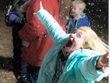 A child playing under faux snowflakes at a Christmas festival near Charlotte, NC.