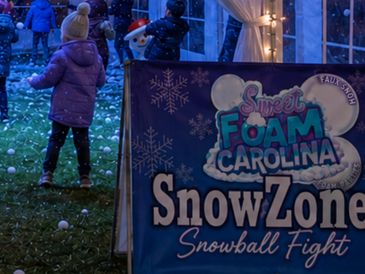 Children playing in an artificial snowball fight zone at night.
