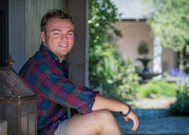 Young man smiling outdoors in a relaxed pose.