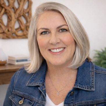 Smiling woman with blonde hair wearing a denim jacket.