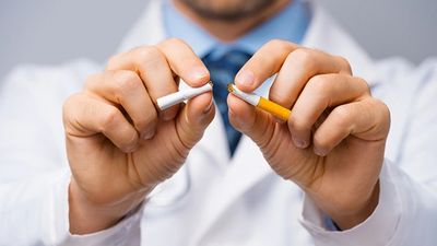 Doctor breaking a cigarette symbolizing quitting smoking.