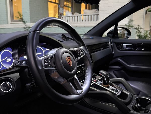 Luxurious Porsche car interior with leather steering wheel and modern dashboard.