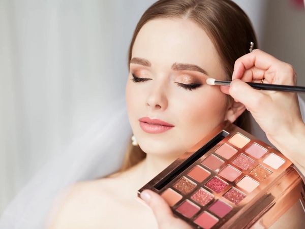 A woman having eyeshadow applied with a makeup brush.