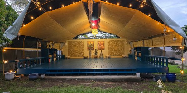 Outdoor stage with warm lighting under a canopy tent.
