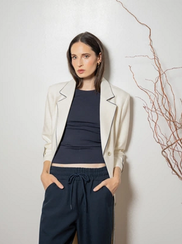 Woman wearing a white blazer over a black top and navy pants.