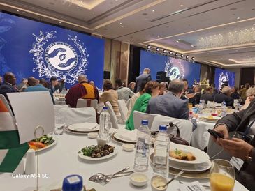 People attending a formal banquet with food and drinks at a decorated venue.