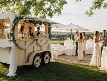 Elegant outdoor wedding bar setup with guests mingling under umbrellas.