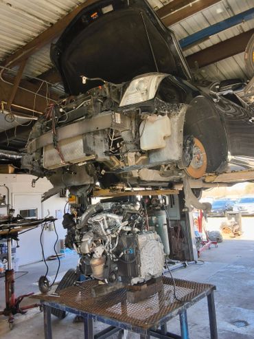 Car with its engine removed and placed on a metal table in a garage.