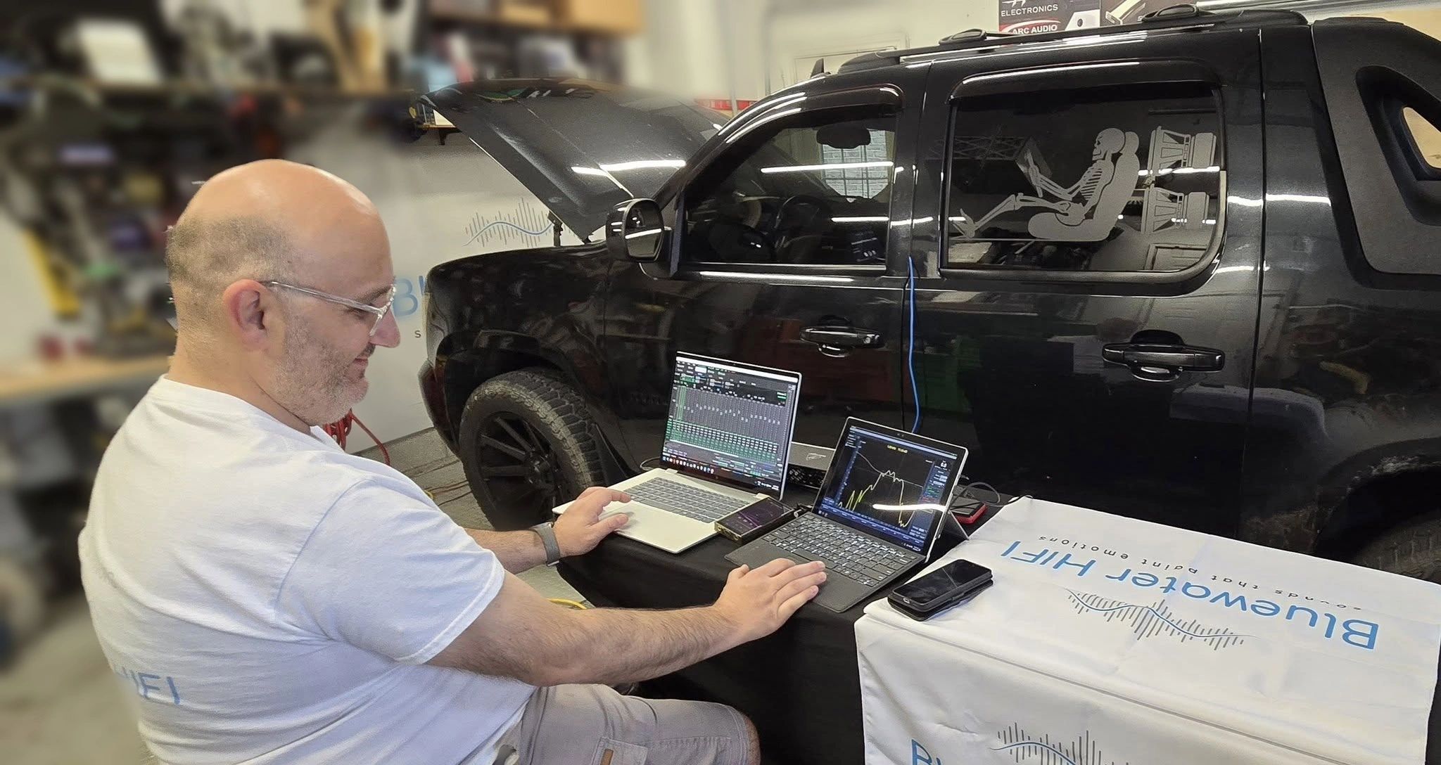 Julian of Bluewater HIFI tuning a car audio DSP beside a Chevy Avalanche in Sarnia, Ontario