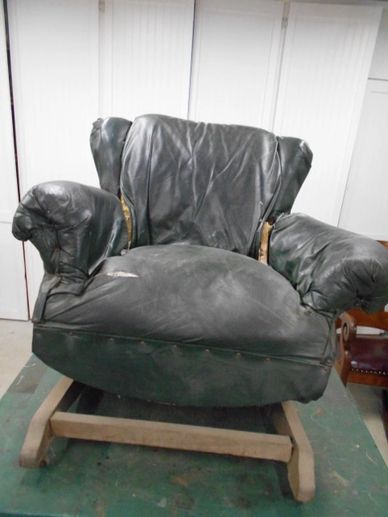 Old, worn-out black leather armchair with visible tears and sagging cushions.